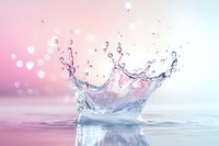 Splashing water crown formation with droplets against pink and blue gradient background, creating dynamic liquid motion and reflection on surface.