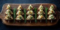 Christmas tree shaped appetizers with cheese and herbs on wooden board, festive holiday party food for winter celebrations.