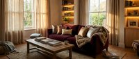 Luxurious living room with burgundy leather sofa, warm lighting, wooden coffee table, and floor-to-ceiling windows with sheer curtains for interior design and home decor projects.