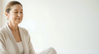 Mature woman with light brown hair, Caucasian ethnicity, wearing beige cardigan, sitting in contemplative pose with eyes closed, expressing calm and mindfulness for wellness and lifestyle content.