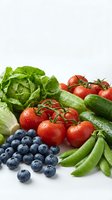 Fresh organic vegetables and fruits including lettuce, tomatoes, cucumbers, peas and blueberries arranged on white background for healthy eating concepts.