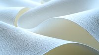 Elegant white paper curves creating soft waves and shadows in minimalist composition with gentle lighting effects and smooth textured surface. Suitable for abstract backgrounds.