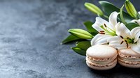 Fresh white lily flowers with delicate French macarons on textured gray stone background, elegant composition for pastry shop advertising and floral design.