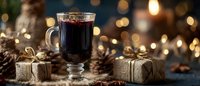 Glass of mulled wine with pine cones and wrapped gifts on dark table with bokeh lights in background creating festive holiday atmosphere.