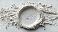 White cosmetic cream texture with circular swirl pattern and scattered powder particles on neutral background for skincare and beauty applications.