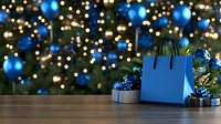 Festive holiday scene with blue shopping bag and wrapped presents against decorated Christmas tree background with blue ornaments and glowing lights.