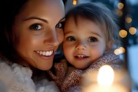 Young mother and toddler daughter share intimate moment with warm bokeh lights creating magical holiday atmosphere, expressing joy and tender connection.