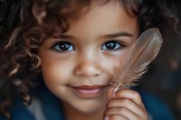 Young mixed-race girl with curly hair holding brown feather, close-up portrait with bright blue eyes and gentle smile for childhood and nature concepts.