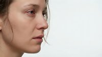 Young Caucasian woman with natural skin texture and freckles in profile view against white background showing authentic beauty and self-acceptance concept.
