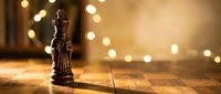Bronze Lady Justice statue with scales and blindfold on wooden surface with warm bokeh lights creating atmospheric legal office background for law firm branding.