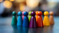 Colorful wooden game pieces arranged in rainbow order against blurred bokeh background, representing diversity, teamwork and inclusion in business concepts.