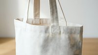 Natural cotton canvas tote bag with handles on wooden surface, eco-friendly reusable shopping bag for sustainable lifestyle and zero waste living.