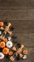 Halloween decorations with orange and white pumpkins, straw scarecrows, spiders and ghost cookies arranged on rustic wooden background with copy space.
