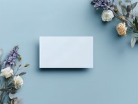 Blank white card mockup with dried flowers arrangement on light blue background, flat lay composition for wedding stationery or feminine branding.