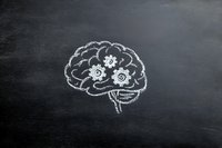Brain with mechanical gears drawn in chalk on blackboard, representing cognitive function and mental processes.