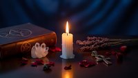 Mystical altar setup with burning candle, spell book, crystal, dried herbs and rose petals for witchcraft rituals and spiritual practices.