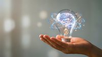 Hand holding illuminated light bulb with glowing brain and digital network connections, representing innovation, creativity, and intelligent solutions for business and technology concepts.