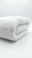 Soft white fluffy towel neatly folded on a light background, showcasing clean cotton texture for spa, hotel, and bathroom concepts.