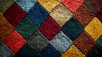 Colorful patchwork knitted pattern with diamond shapes in red, blue, yellow, green and brown wool texture creates cozy winter background.