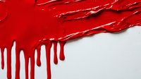 Bright red paint drips and runs down white surface creating dramatic contrast and dynamic movement pattern. Artistic abstract background with liquid texture effect.