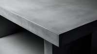 Modern concrete table corner detail showing industrial minimalist design with smooth gray surface and clean geometric lines for contemporary interior spaces.