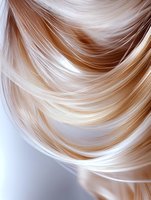 Smooth flowing blonde hair strands creating elegant waves and curves against light background, showcasing natural shine and healthy texture for beauty and haircare concepts.