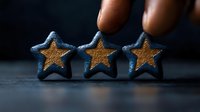 Hand placing golden star rating symbols on dark surface representing customer feedback, quality assessment, and business performance evaluation.