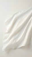 Soft white fabric with elegant flowing folds and gentle shadows creating minimalist textile background for fashion and interior design projects.