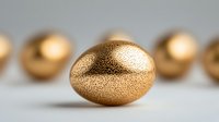 Golden metallic egg with textured surface on blurred background, symbolic of wealth, prosperity and luxury investment concept. Financial growth metaphor.