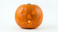 Carved orange pumpkin jack-o-lantern with glowing candle light inside, isolated on white background for Halloween decorations and autumn designs.