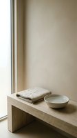 Minimalist windowsill with folded linen cloth and ceramic bowl on natural wood shelf, neutral beige interior design, spa and wellness styling.
