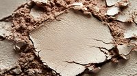 Crushed beige face powder makeup with scattered fragments showing texture and application for beauty cosmetics and skincare routine.