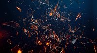 Dramatic explosion of shattered glass fragments with fiery orange sparks and glowing embers against dark background for dynamic design projects.