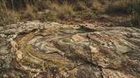 Ancient rock surface with natural weathering patterns and circular formations in desert landscape for geology and nature projects.