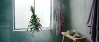 Serene bathroom interior with hanging eucalyptus bundle, wooden stool, ceramic bowls and soft towels creating spa-like wellness atmosphere for relaxation.