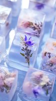 Purple wildflowers and herbs frozen in clear ice cubes create an ethereal composition with soft blue and lavender tones, suitable for cocktail and beverage photography.