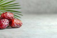 Fresh red dates arranged with palm leaf on light marble background, selective focus with copy space for text. Natural healthy snack concept.