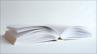 Open book with blank white pages spread out against light background, creating minimalist composition with subtle shadows and curves of paper sheets.