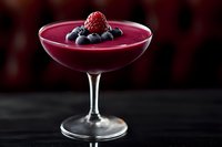 Elegant berry smoothie in cocktail glass garnished with fresh blueberries and raspberry against dark background, perfect for menu photography.