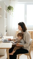 Working mother with toddler child using laptop computer at home office desk. Remote work parenting balance concept for modern family lifestyle.