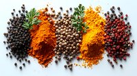 Colorful spices and peppercorns arranged in rows on white background - turmeric, paprika, black, white and pink peppercorns with fresh herbs create vibrant composition.