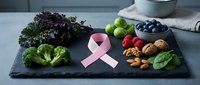 Healthy organic foods arranged on slate board with pink awareness ribbon promoting cancer prevention nutrition and wellness lifestyle choices.