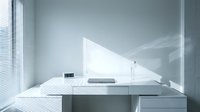Modern minimalist white office desk with laptop and lamp in bright contemporary workspace with venetian blinds casting geometric shadows.