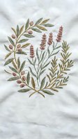 Delicate hand embroidered botanical arrangement featuring lavender sprigs, olive branches and berries on white linen fabric for home decor and craft projects.