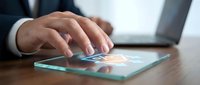 Businessman hand touching digital tablet screen with glowing technology interface icons on modern office desk for business communication and connectivity.