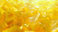 Vibrant yellow crystalline structure with translucent facets creating a luminous abstract background of golden amber hues and geometric shapes.