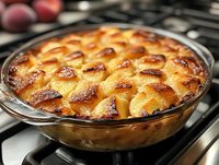 Golden brown peach cobbler in glass baking dish fresh from oven, showing bubbling fruit filling and latticed buttery pastry top with caramelized edges.