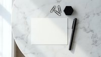 Minimalist workspace with blank white paper, black pen and office supplies on elegant marble surface for business presentations and creative projects.