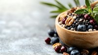 Fresh mixed berries and nuts in wooden bowl with rosemary garnish on rustic gray background, selective focus with copy space for healthy eating concept.