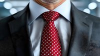 Close-up of businessman wearing elegant black suit with red patterned silk tie and white collar shirt, representing professional corporate style and formal attire.